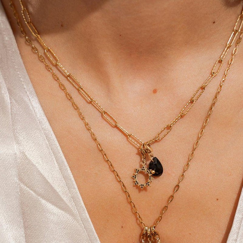Charm soleil en acier doré orné de strass noirs