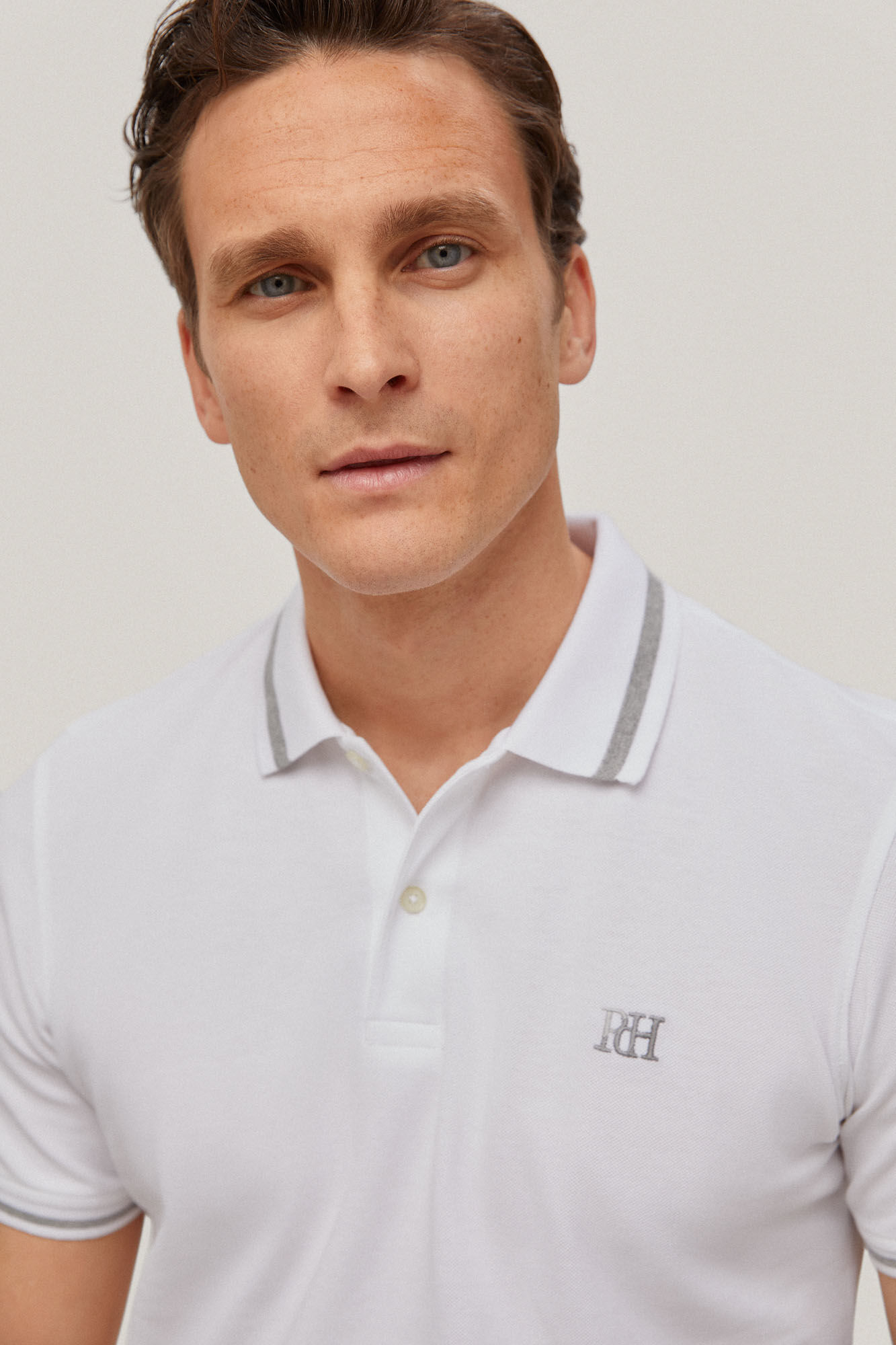 Camisa polo com gola pontuda e logotipo na cor branca.