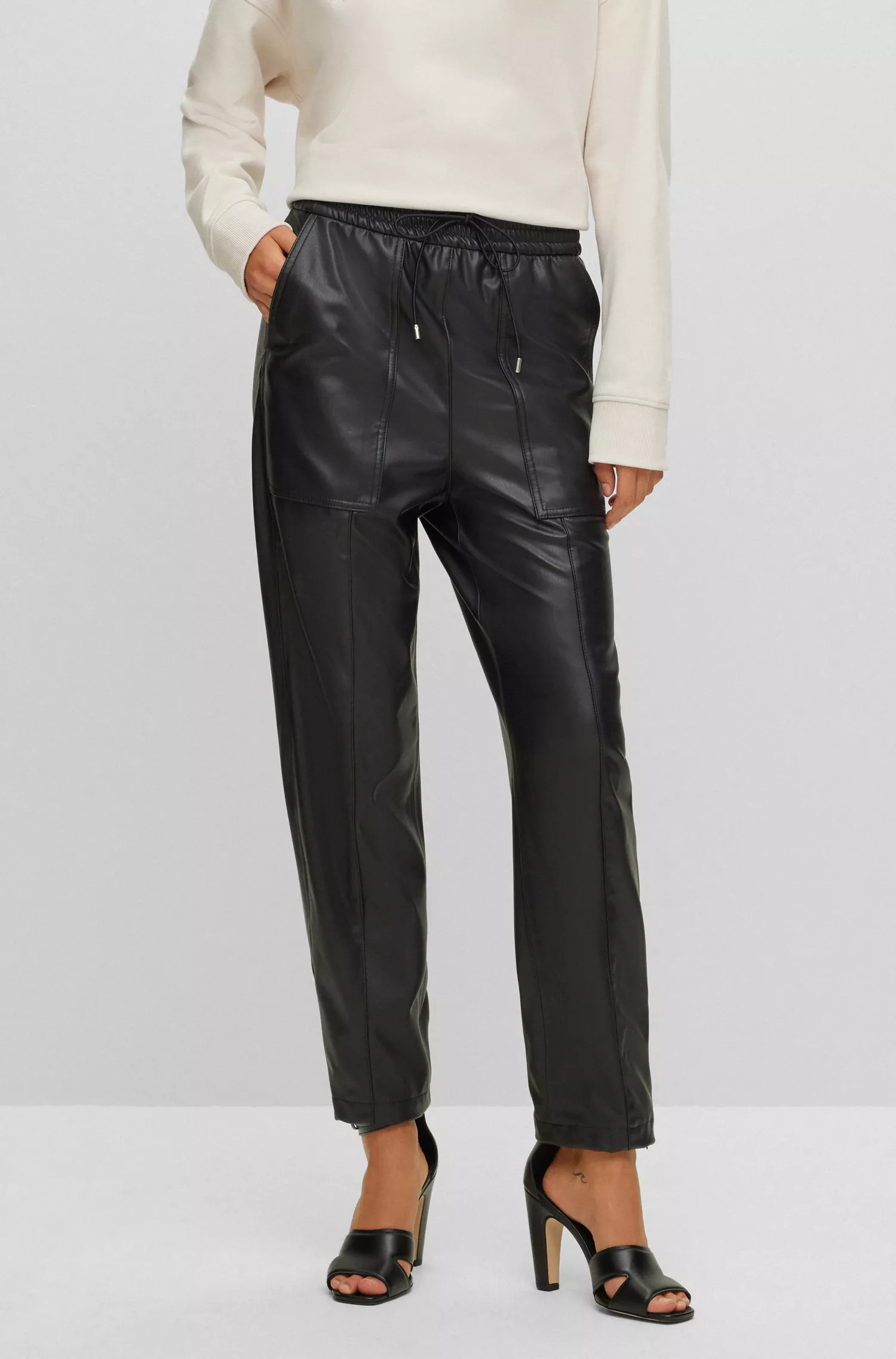 Calça BOSS laranja, corte relaxado, em tecido revestido, com cintura ajustável por cordão.