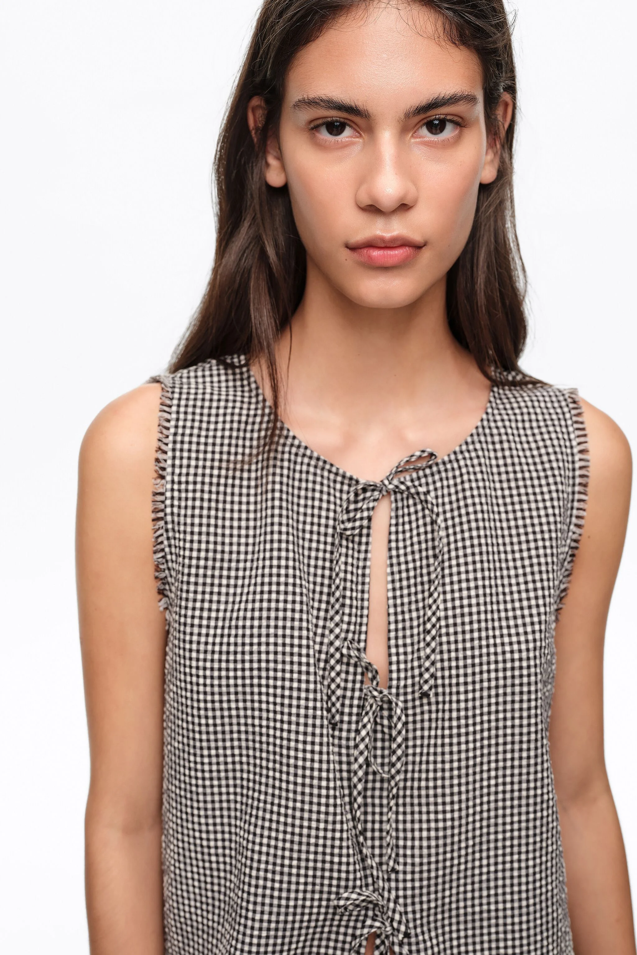 Blusa xadrez preta com laços e detalhes desfiados.