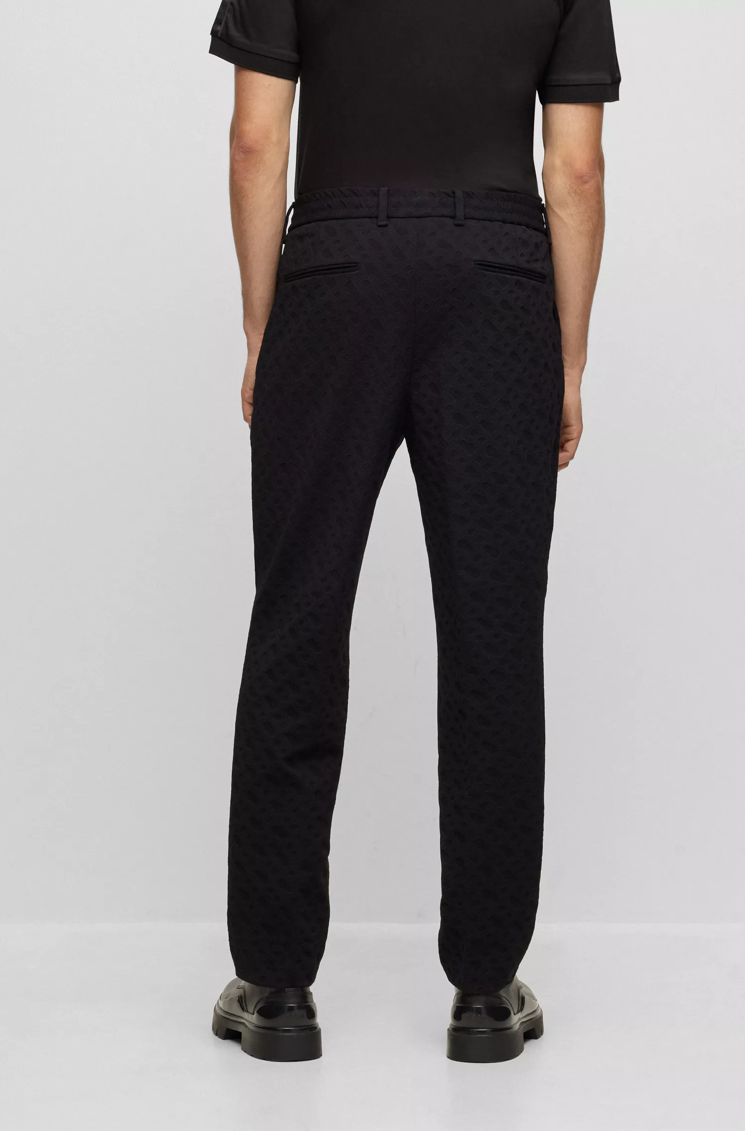 Calça BOSS preta de corte relaxado em tecido elástico com monograma.