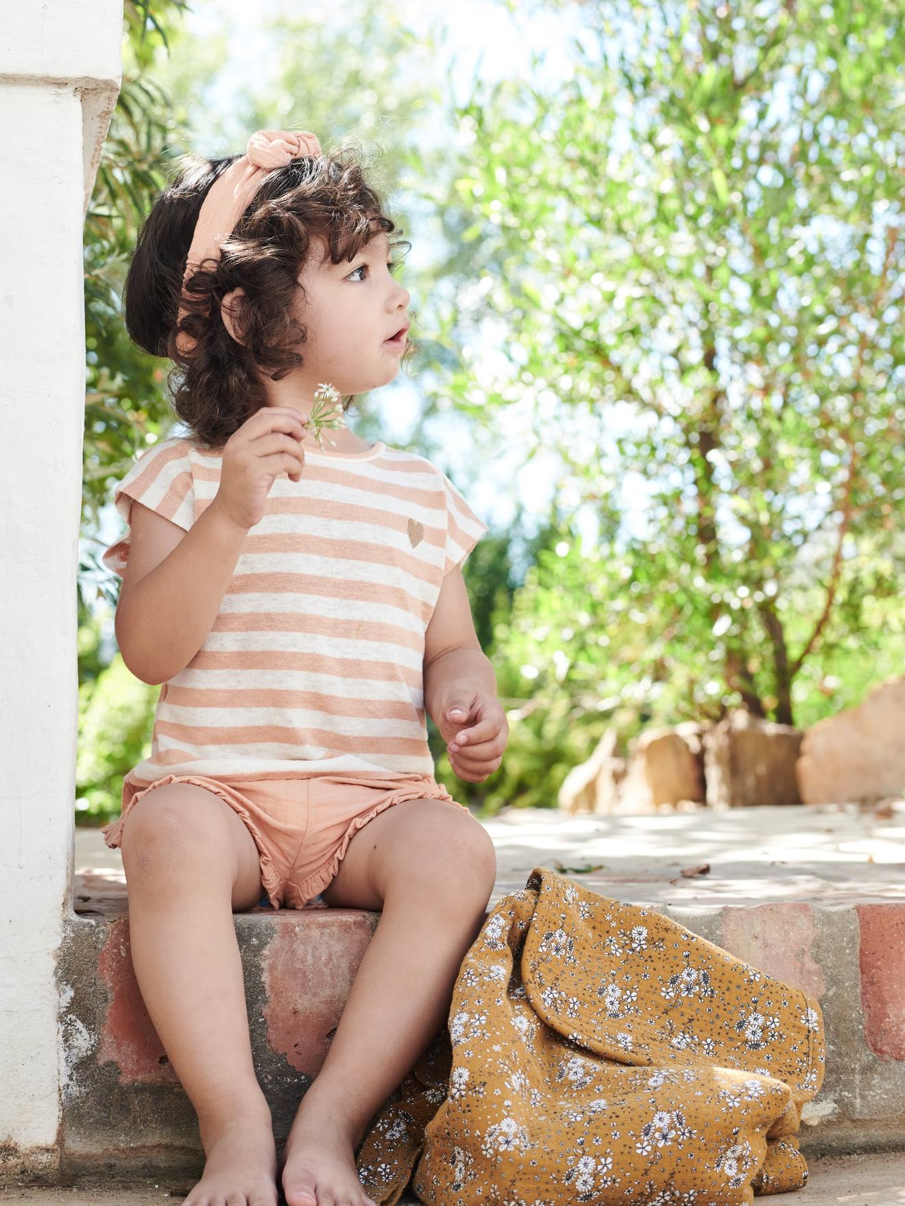 Roupa de bebê: shorts, camiseta listrada e faixa de cabelo verde-acinzentada.