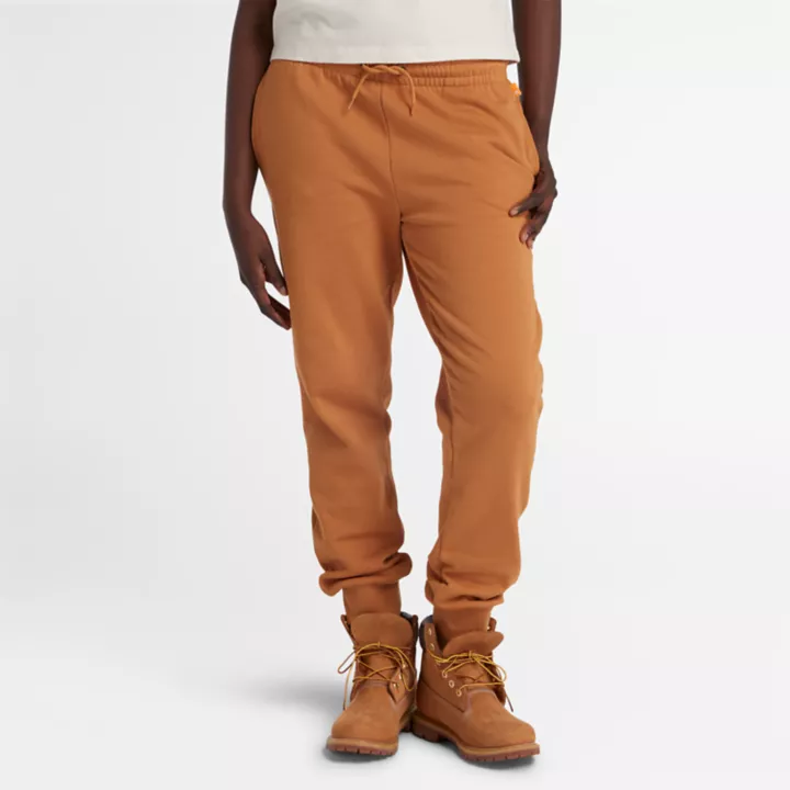 Calça de fato de treino feminina com bordado de árvore no tom amarelo escuro.