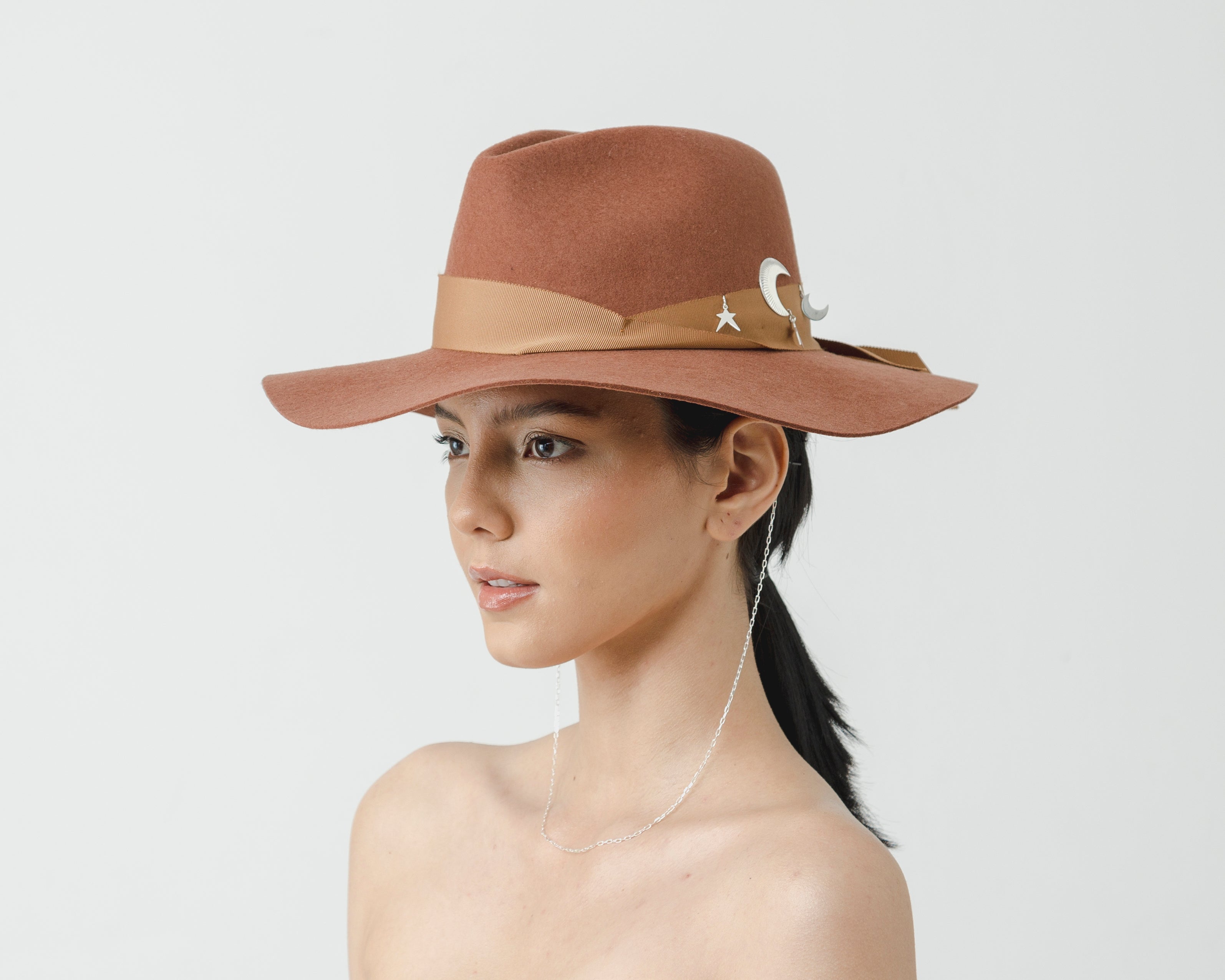 Chapeau classique à longs bords avec une chaînette argentée ornée de lunes et d'étoiles.