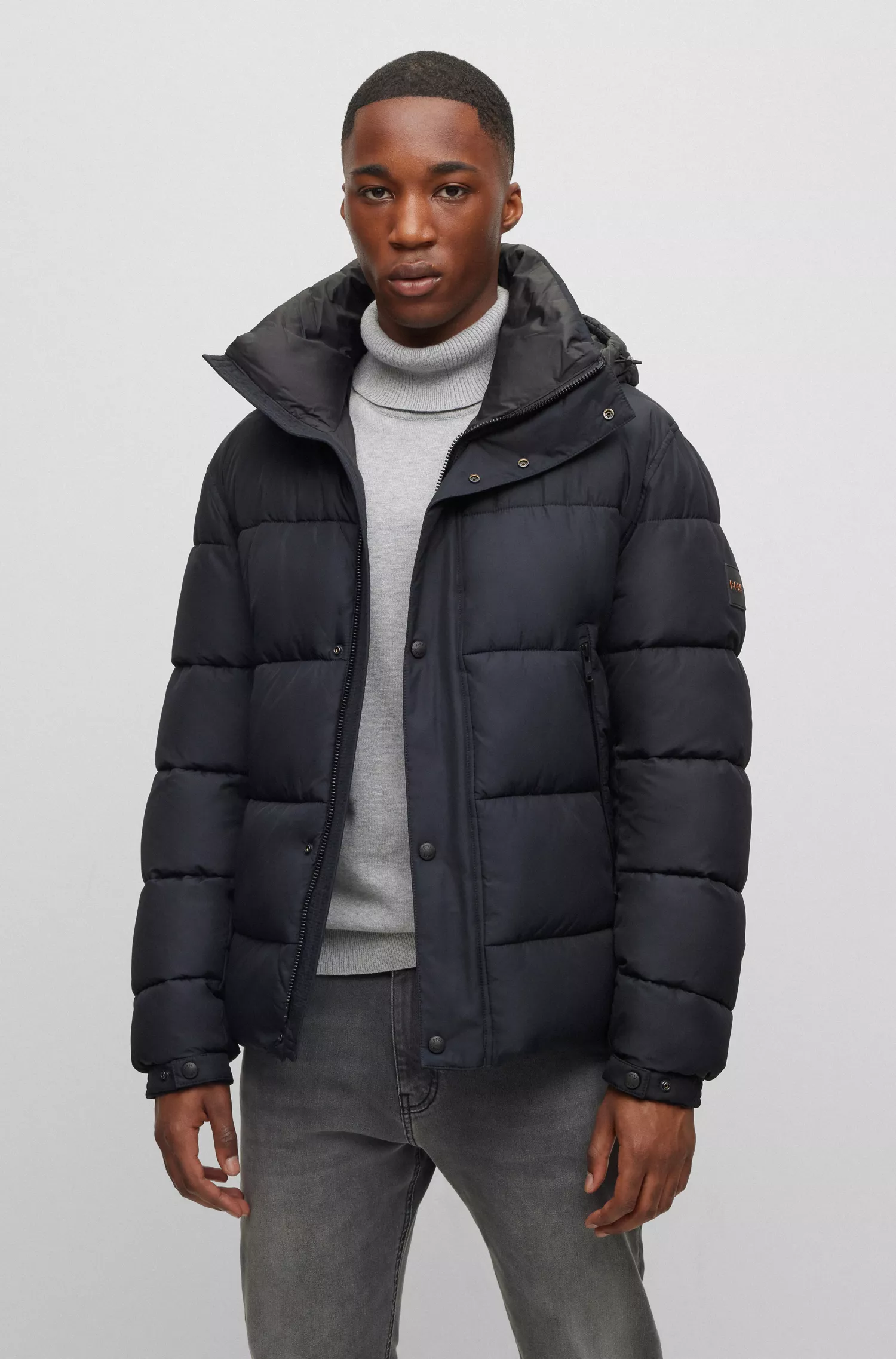 Jaqueta puffer com capuz BOSS laranja, repelente à água e com emblema da marca.