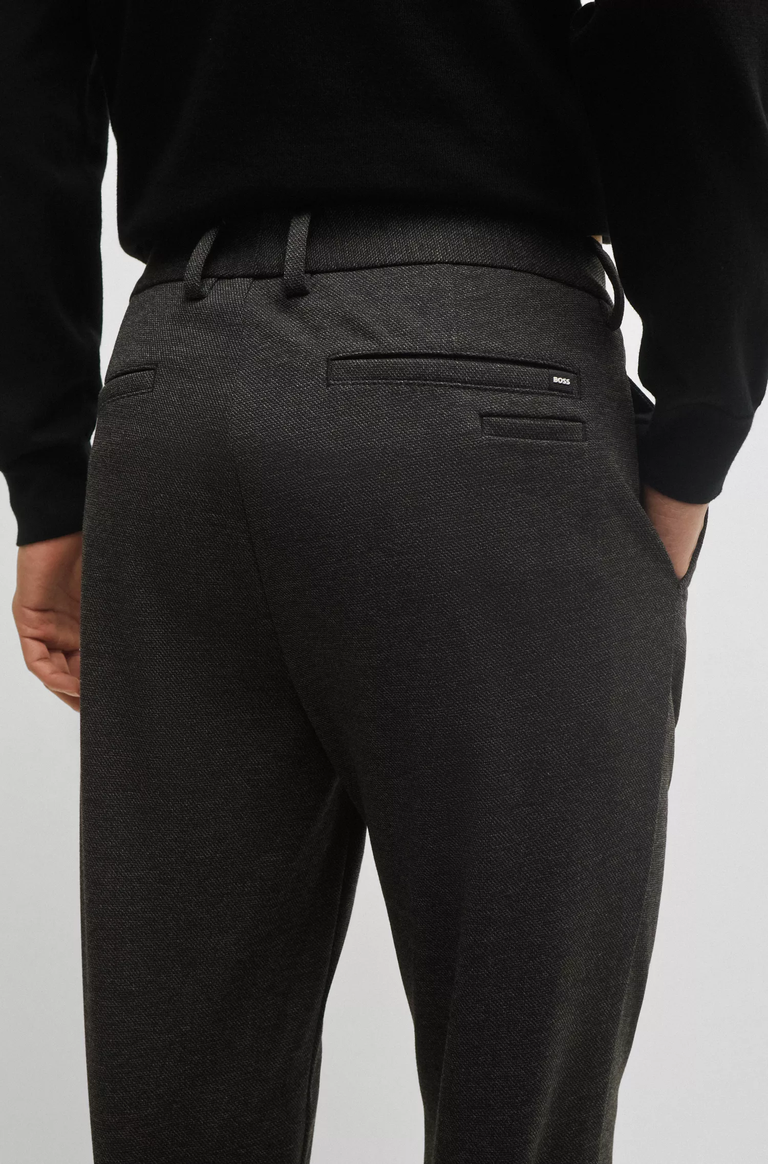 Calça BOSS preta, corte slim, em tecido estruturado de alta performance com elasticidade.