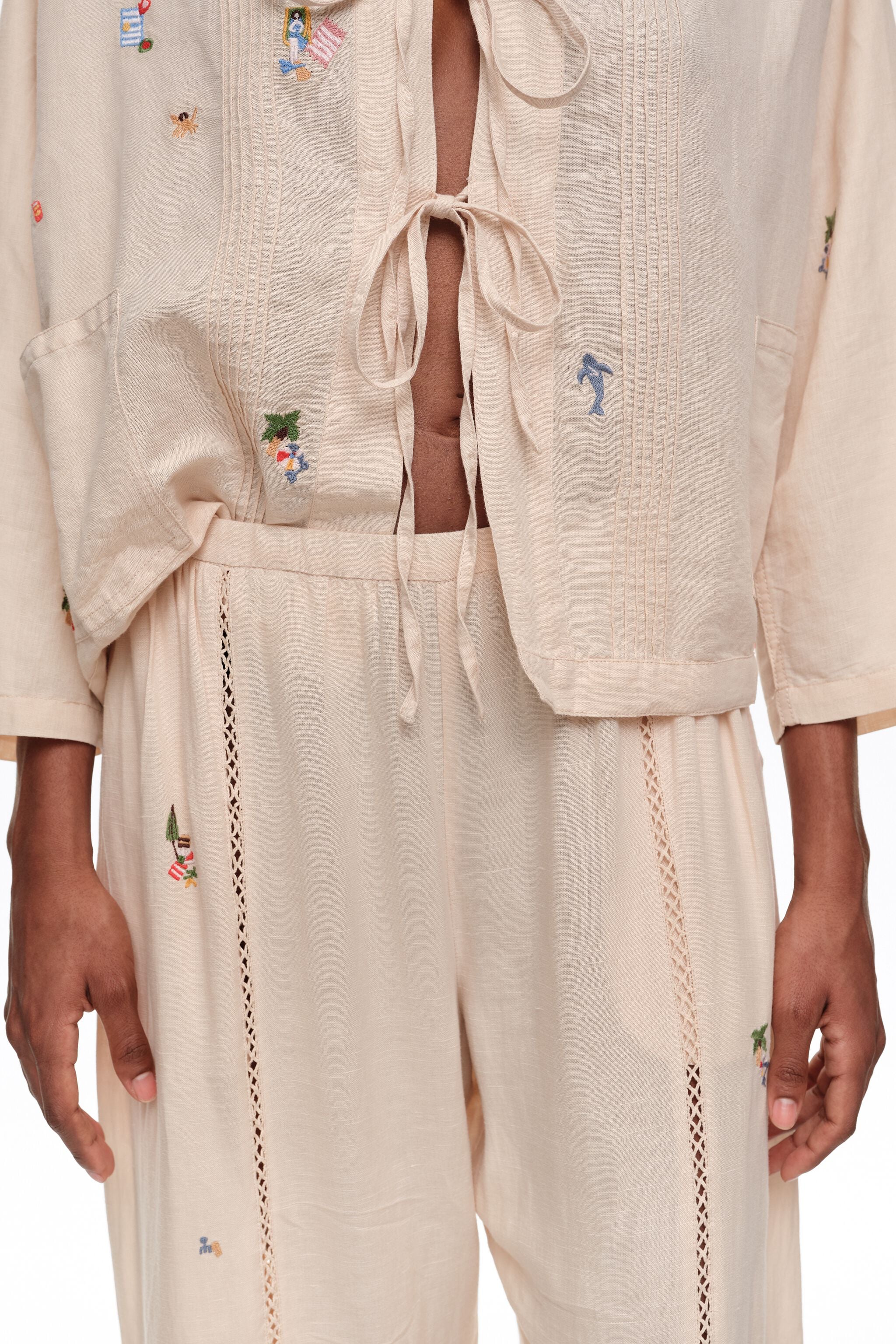 Calças largas de linho branco com renda e mini bordados.