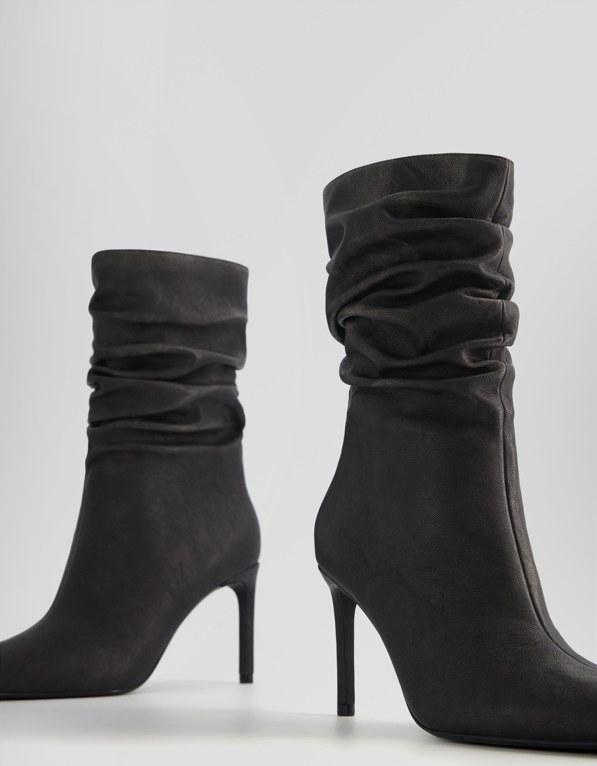 Botas de cano curto com salto agulha e modelagem folgada