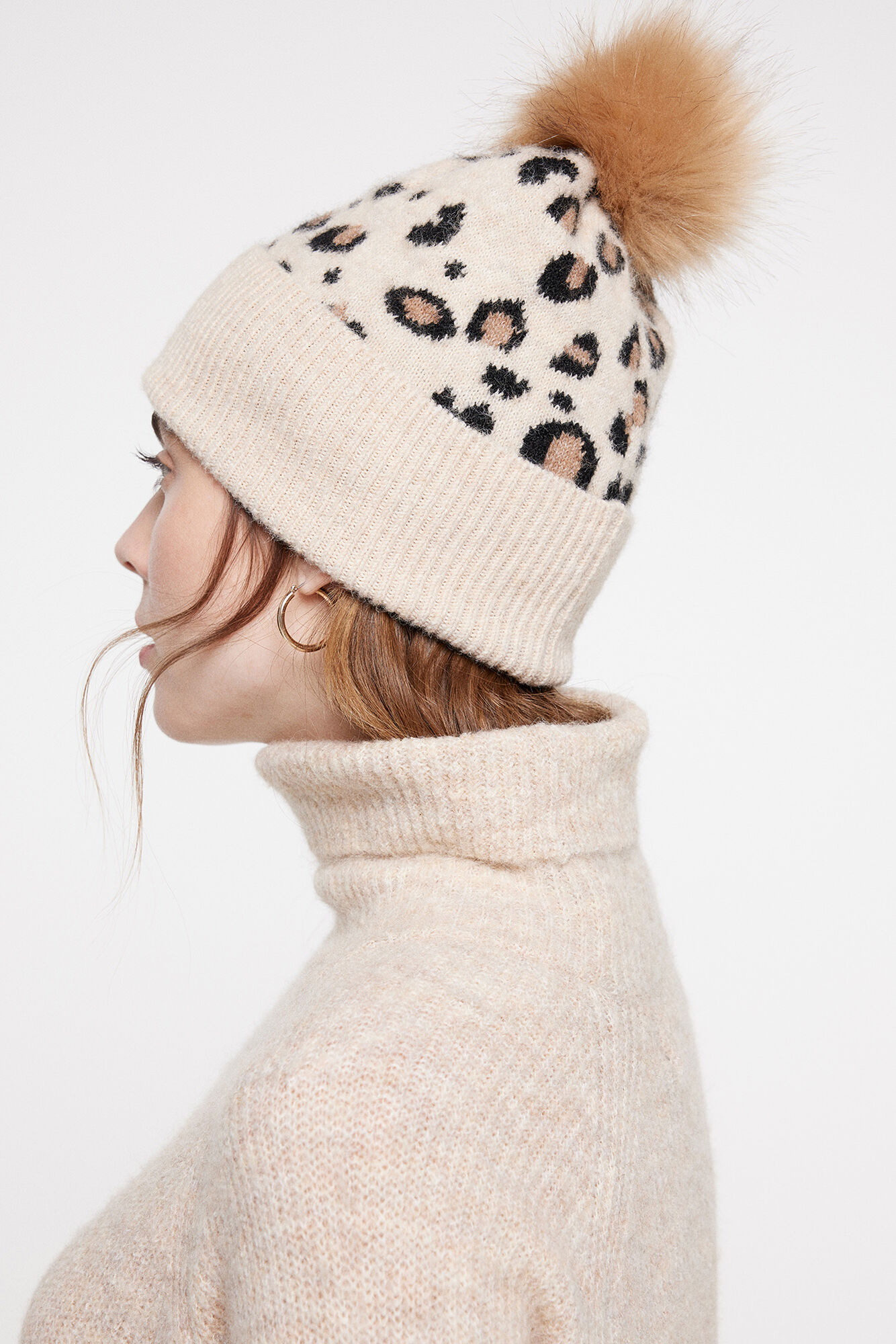 Gorro de tricô com estampa. Possui pompom e aba dobrada.