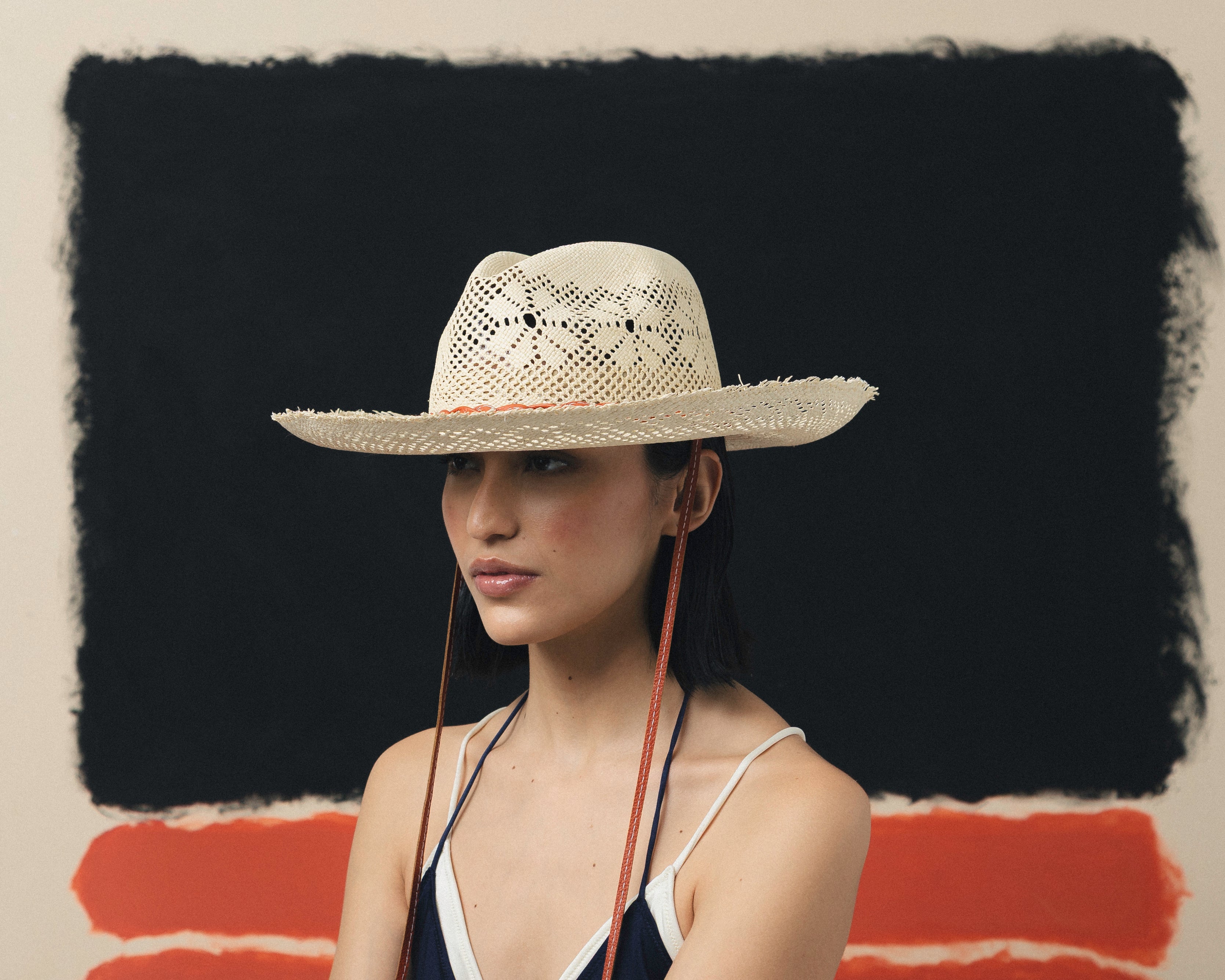 Chapeau Panama à long bord en cuir tressé à mailles ouvertes et effilochées.