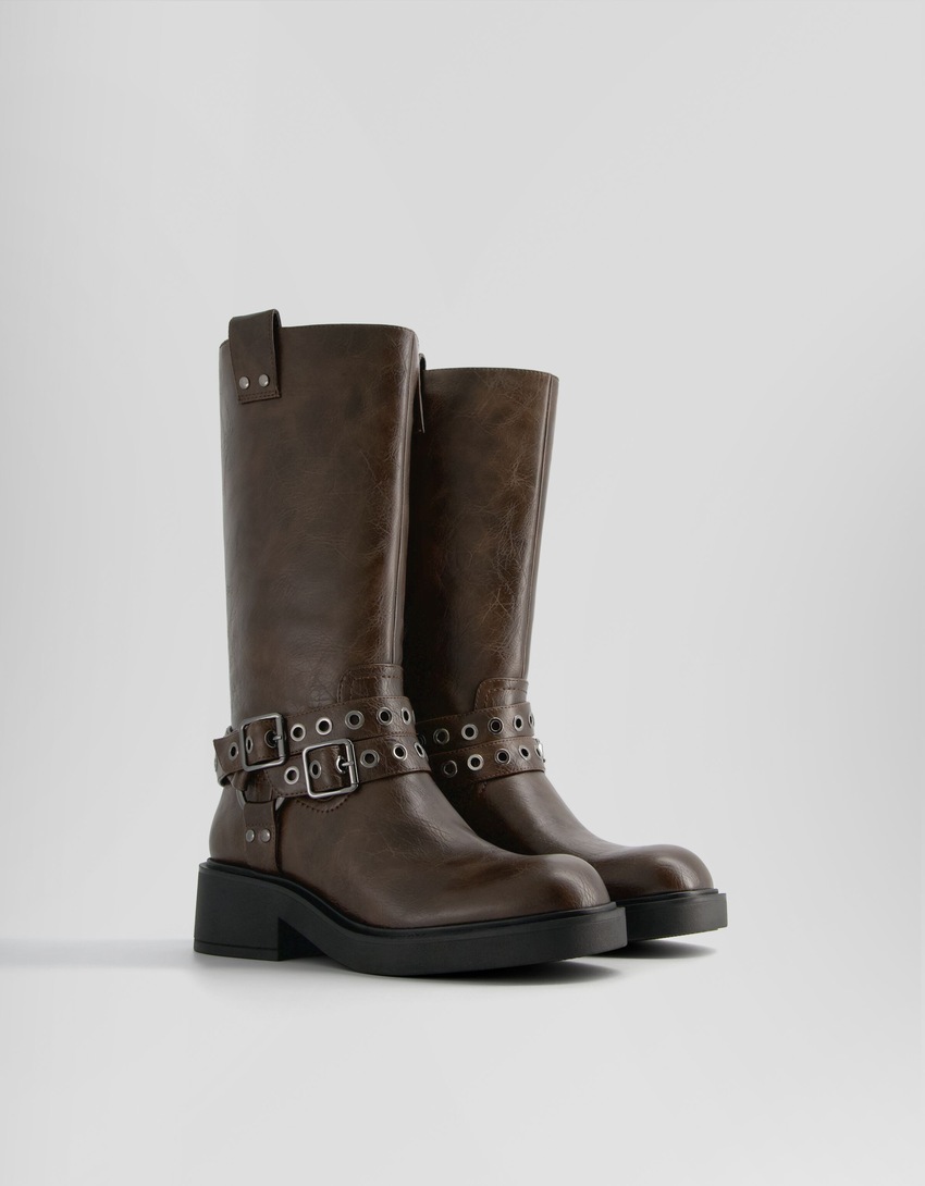 Botas de motociclista com fivelas e ilhós.