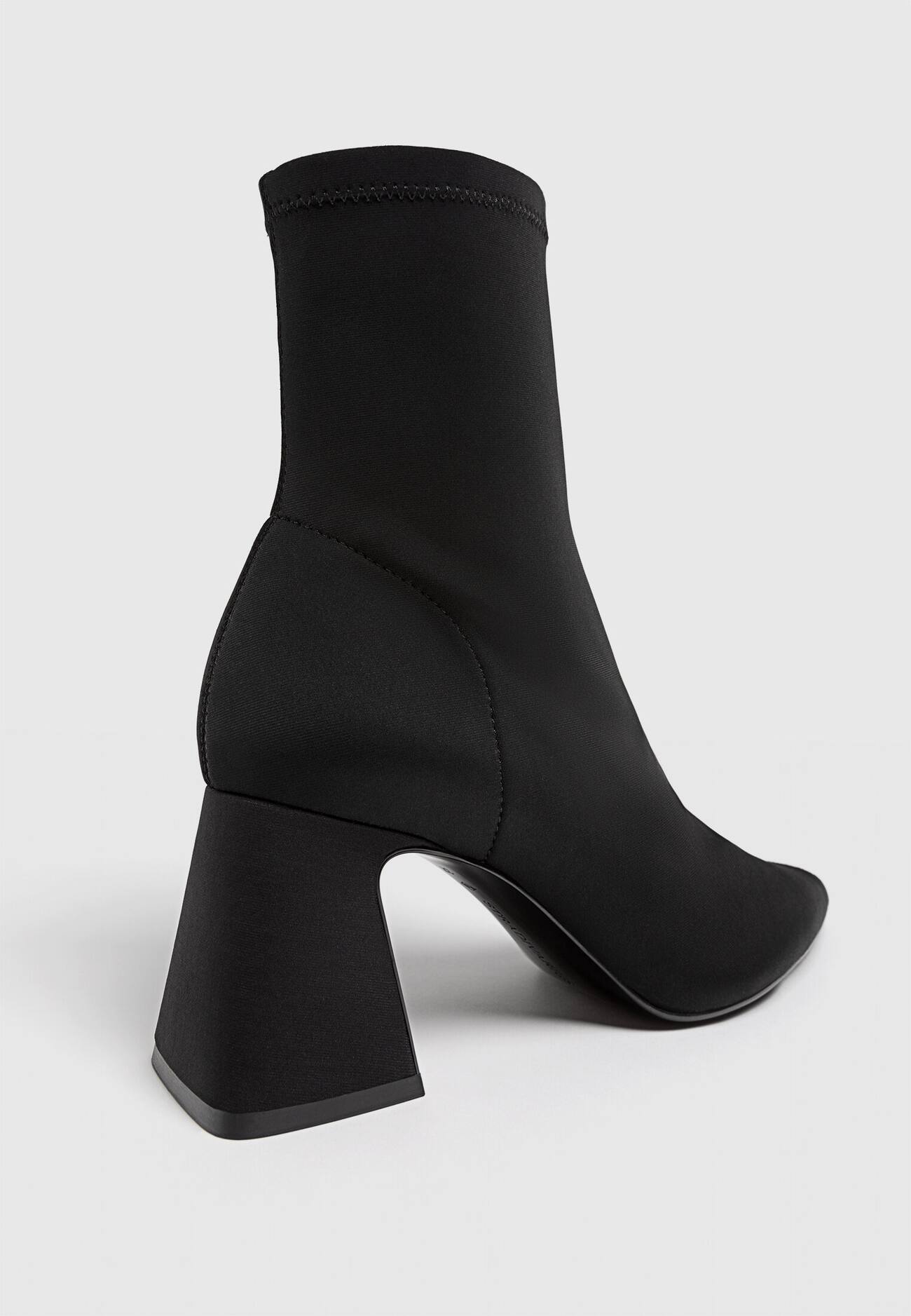 Botas pretas de cano curto com salto alto e cano curto, em tecido elástico.
