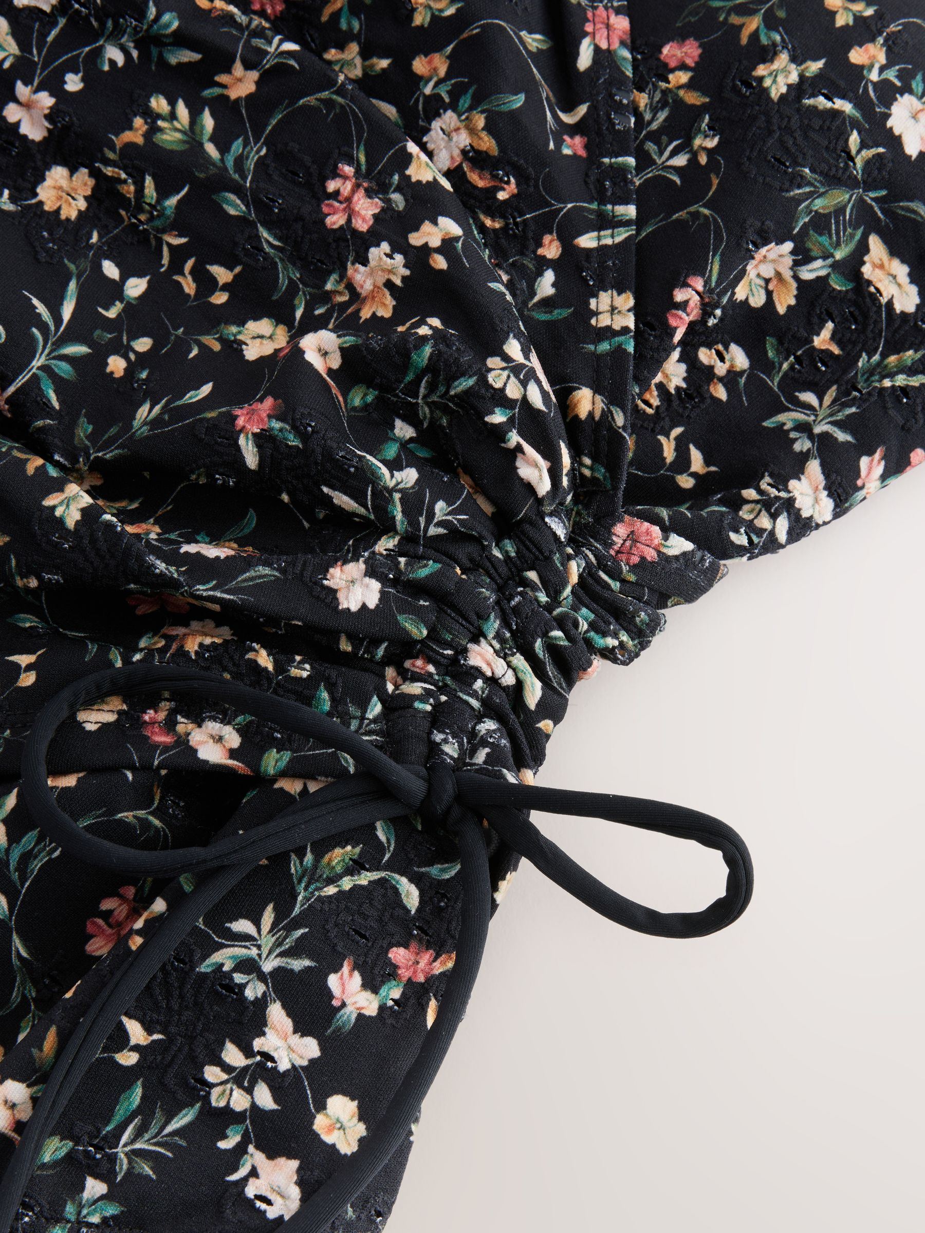 Zwart met broderie en fijne print - Badpak met vormgevende zijrimpeling en buikcorrectie