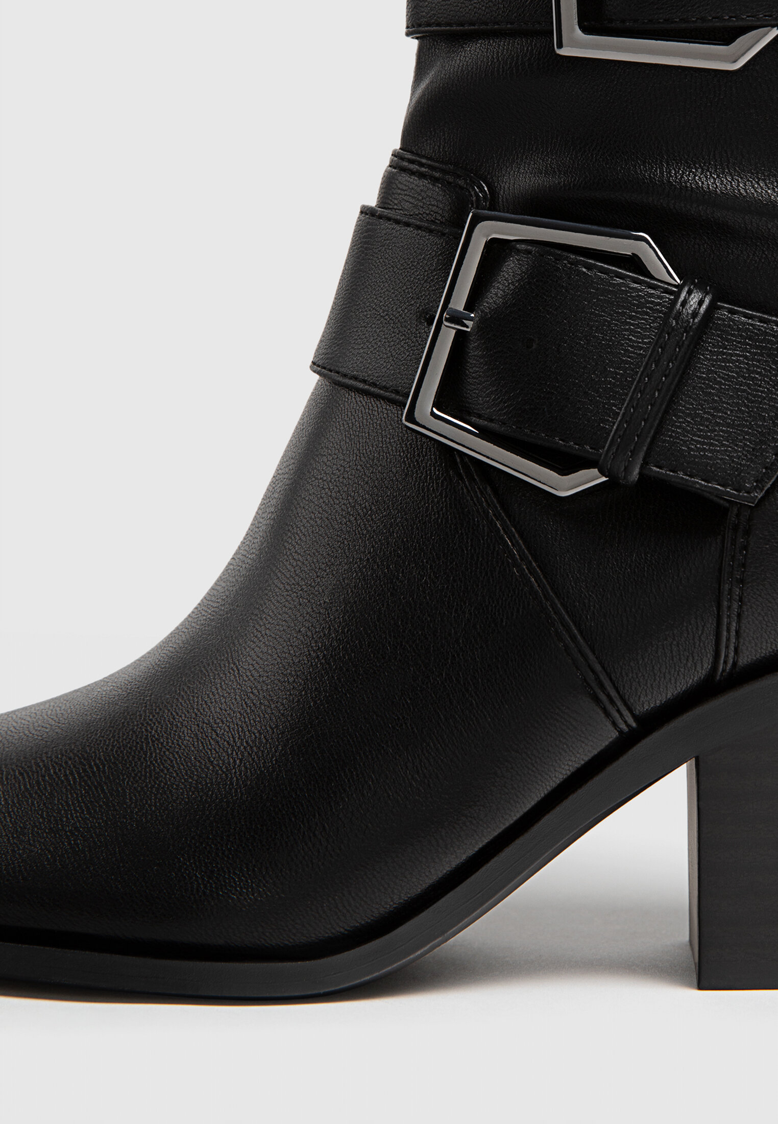 Botas pretas de cano curto com salto alto e fivelas.
