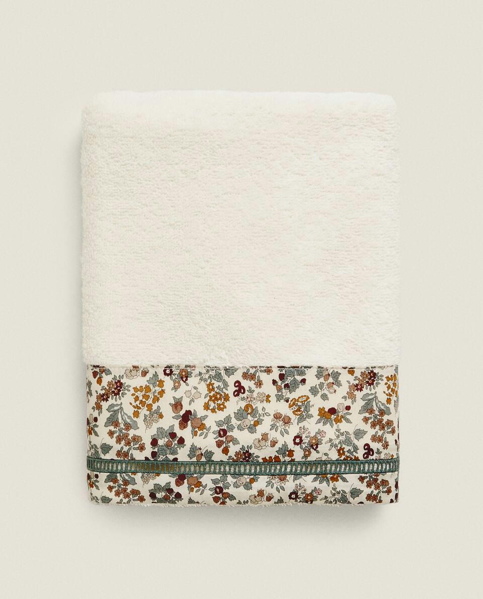 Toalha infantil de algodão com estampa floral e borda.