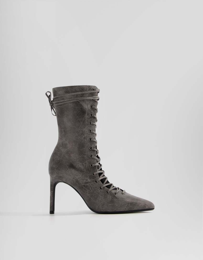 Botas de cano curto com cadarço, salto agulha e zíper.