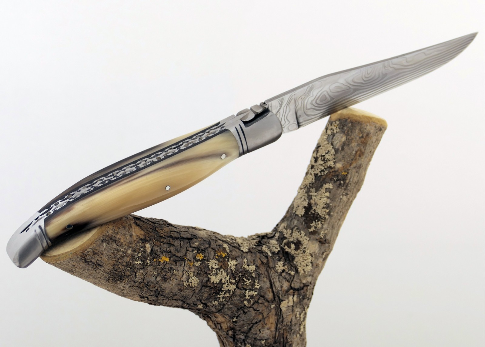 Couteau Laguiole prestige avec un manche en pointe de corne blonde et mitres en acier inoxydable et lame Damas