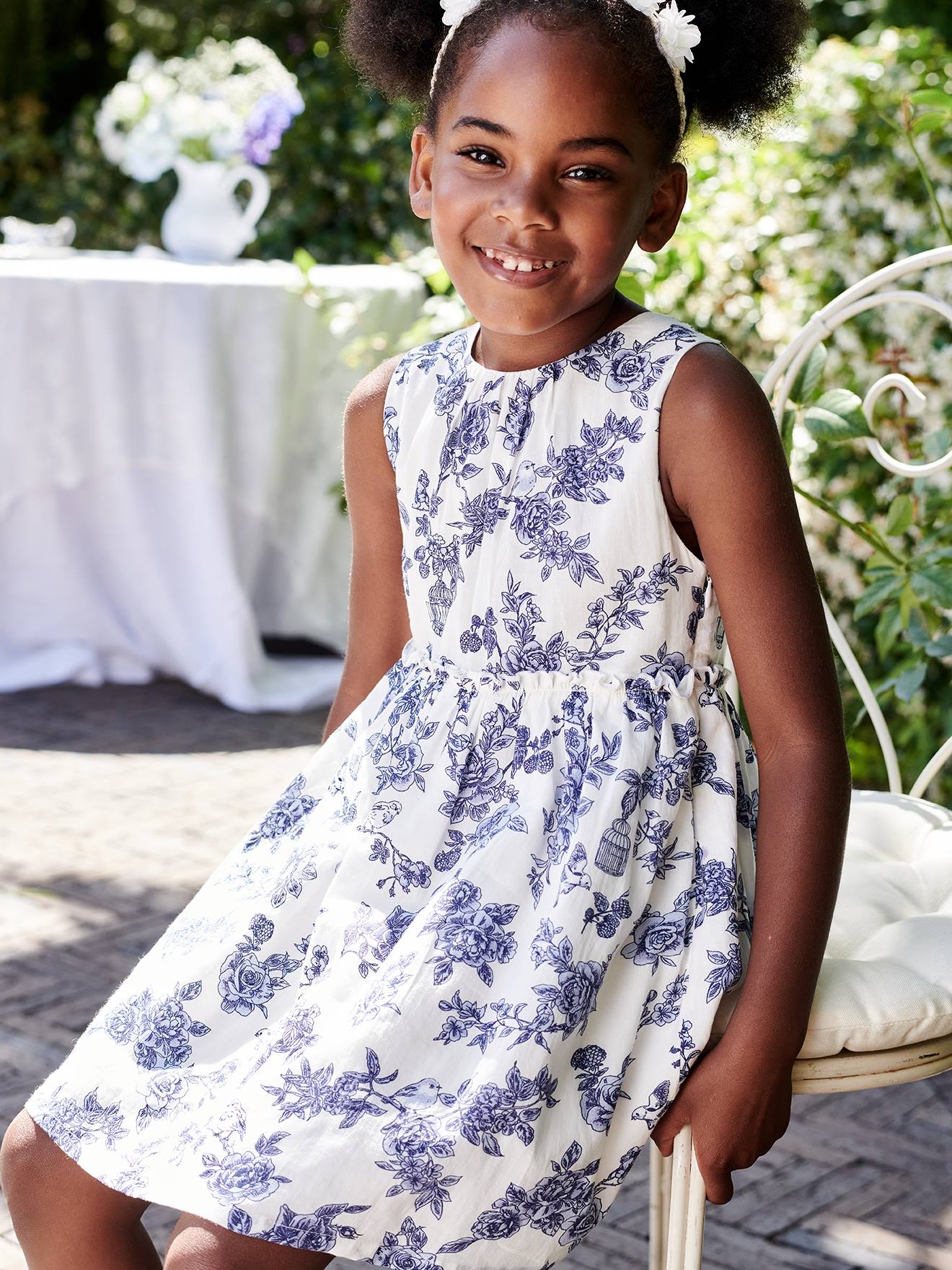 Vestido de festa infantil com flores e laço nas costas, na cor branco-creme.