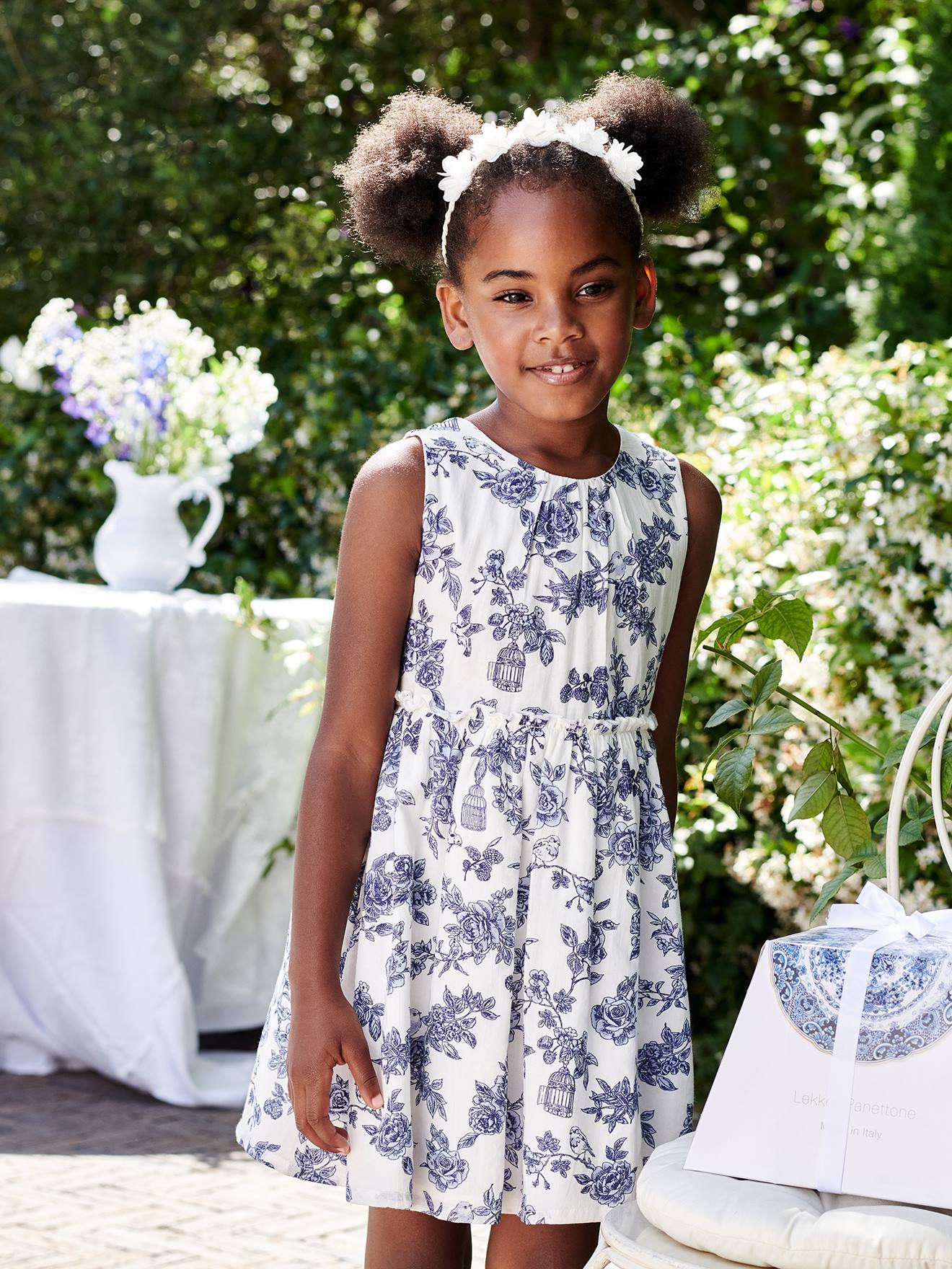 Vestido de festa infantil com flores e laço nas costas, na cor branco-creme.