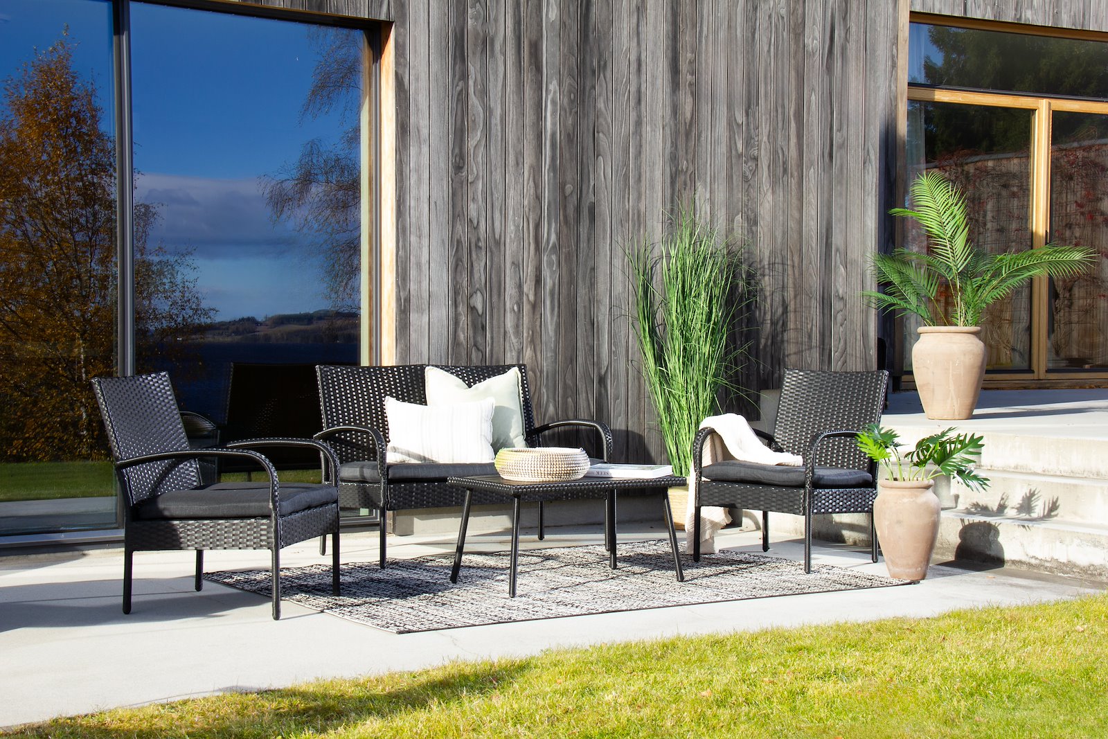 Sardinia utesofagruppe Sofa, to stoler og bord. Sort kunstrotting og grå puter og sort polywood bordplate.