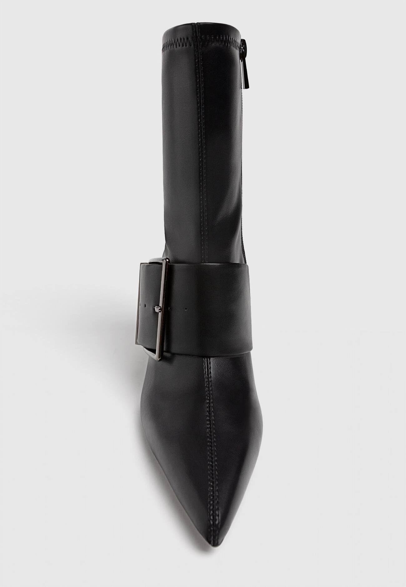 Botas pretas de cano curto com salto alto e fivelas.