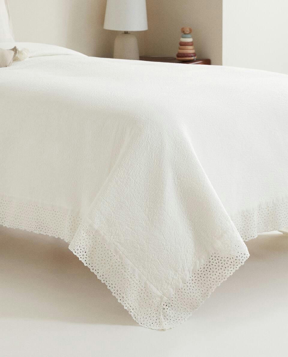 Colcha de algodão com detalhes bordados e franzidos.