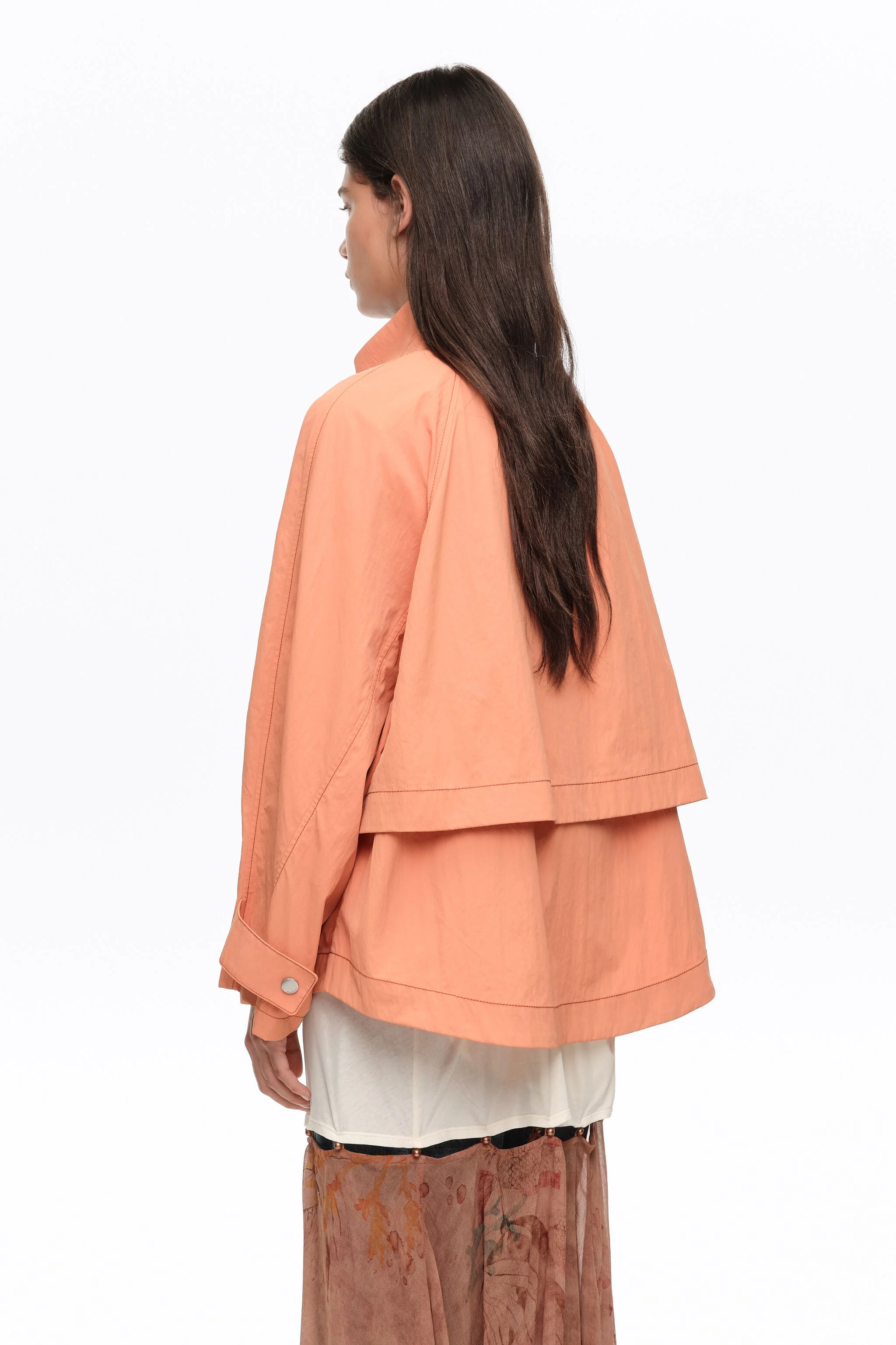 Trench coat curto, laranja, fluido, com gola alta.