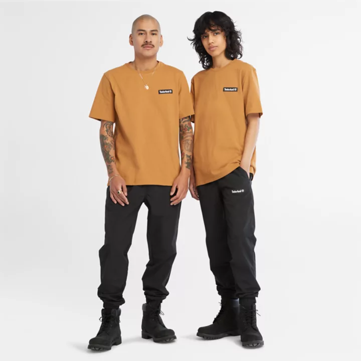Camiseta unissex de tecido pesado com emblema na cor amarela.