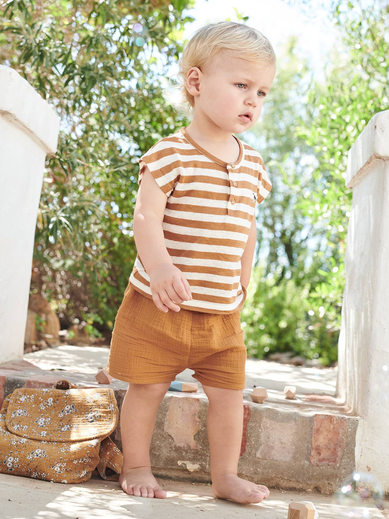Roupa de bebê: camiseta listrada e shorts azul-claro liso.