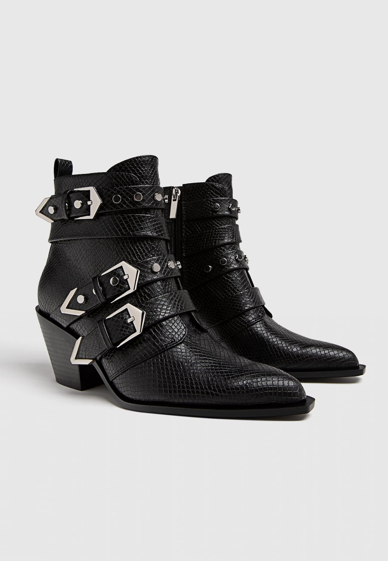Botas pretas de cano curto com salto alto e fivelas.