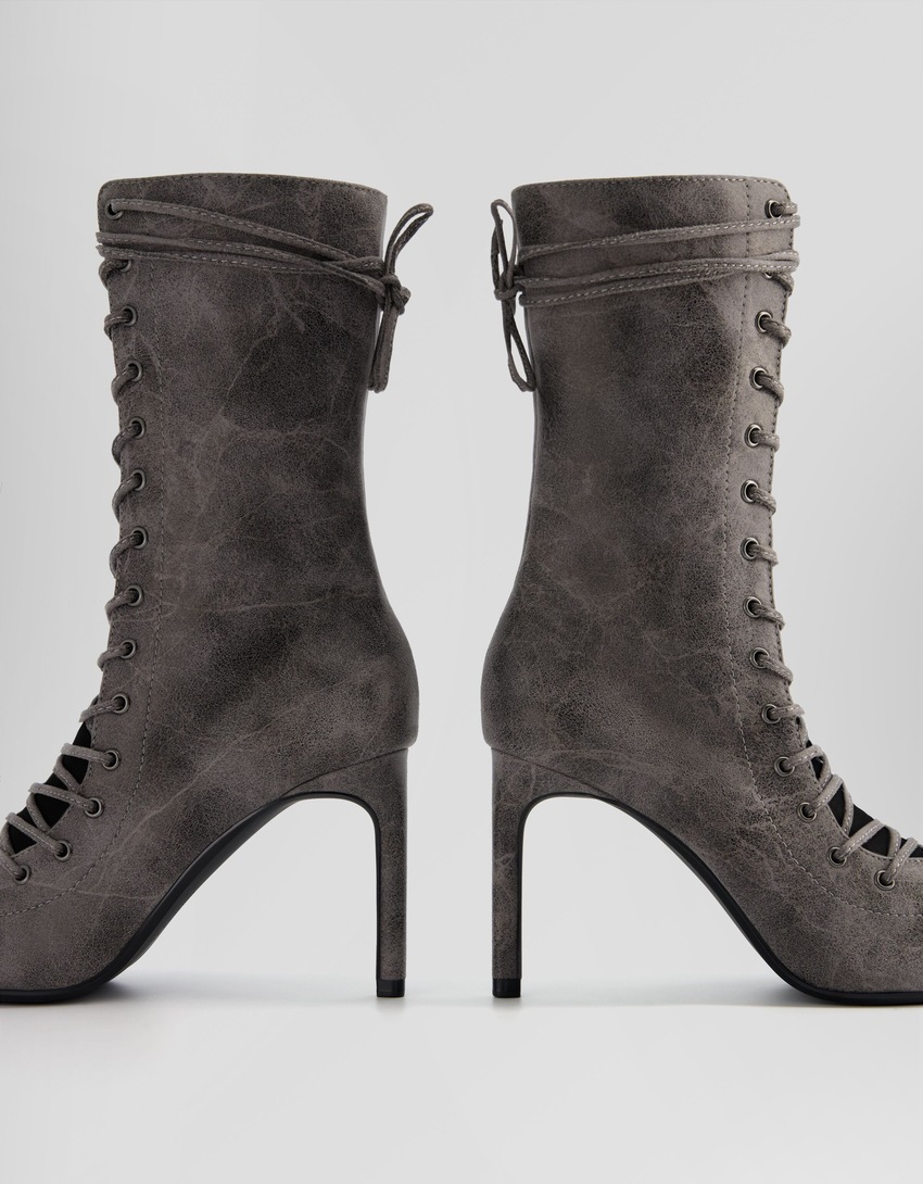 Botas de cano curto com cadarço, salto agulha e zíper.